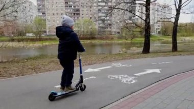 Küçük çocuk ilkbaharın başlarında bisiklet parkında scooter kullanıyordu.