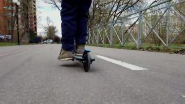 Küçük çocuk ilkbaharın başlarında bisiklet parkında scooter kullanıyordu.