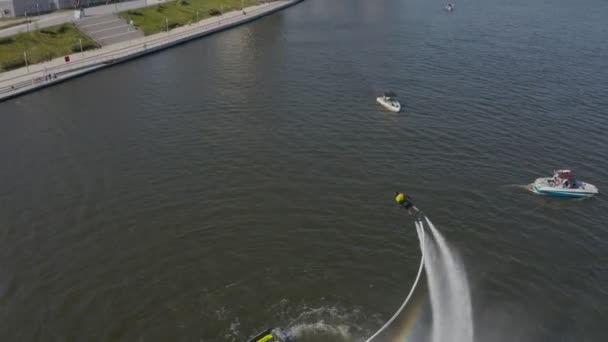 Muž přeletí řeku na skútru a ponoří se do vody. Flyboarding je nový extrémní vodní sport. muž předvádí triky za letu. Velkolepé sportovní převraty. letecký pohled — Stock video