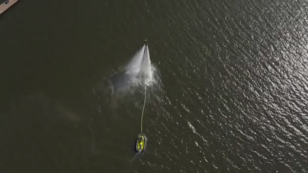 Un homme survole la rivière sur un flyboard et plonge dans l'eau. Le Flyboard est un nouveau sport nautique extrême. un homme fait des tours en vol. Des coups d'État sportifs spectaculaires et des virages. vue aérienne — Video