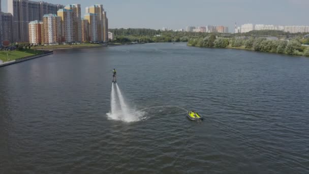 Człowiek przelatuje nad rzeką na desce i nurkuje w wodzie. Flyboarding to nowy ekstremalny sport wodny. Człowiek wykonuje sztuczki podczas lotu. Spektakularne sportowe zamachy stanu i zakręty. widok z powietrza — Wideo stockowe