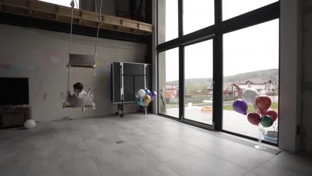 Dziecko huśtające się na huśtawce we wnętrzu budynku mieszkalnego podczas pandemii — Wideo stockowe