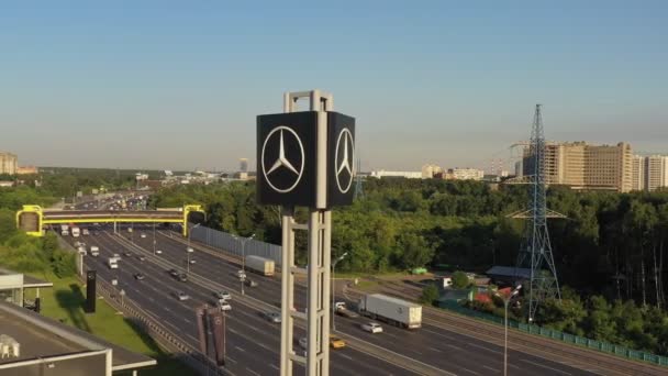 Mercedes-Benz Emblem auf einem Werbemast neben der Autobahn an einem sonnigen Tag, bei Sonnenuntergang. Luftaufnahme. Nahaufnahme — Stockvideo