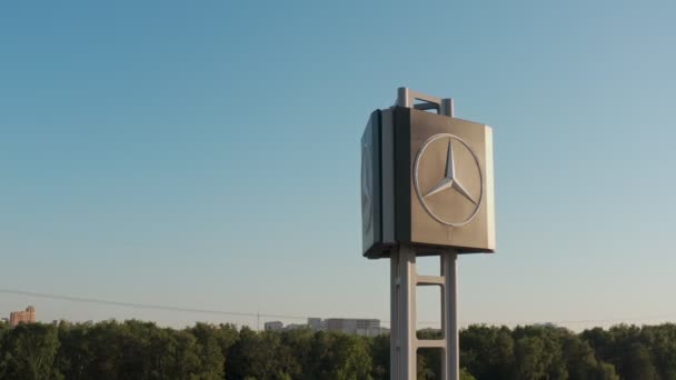 在阳光灿烂的一天，日落时分，梅赛德斯-奔驰标志在高速公路旁边的一个广告杆上。航拍。特写镜头 — 图库视频影像