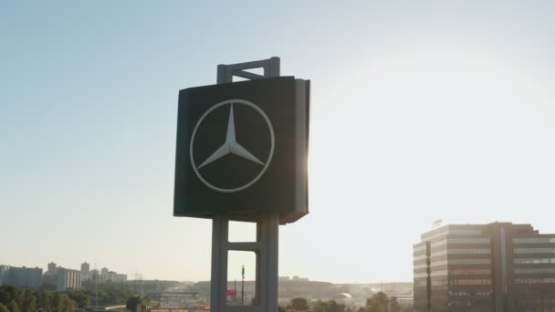 Mercedes-Benz embleem op een reclamebord naast de snelweg op een zonnige dag, bij zonsondergang. vanuit de lucht gezien. close-up — Stockvideo