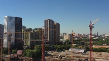 Moskova 'nın müreffeh bir bölgesinde tamamlanmış tuğla apartmanların zeminine karşı yeni bir konut kompleksi inşa etme sürecinde olan birkaç vinç. hava görünümü