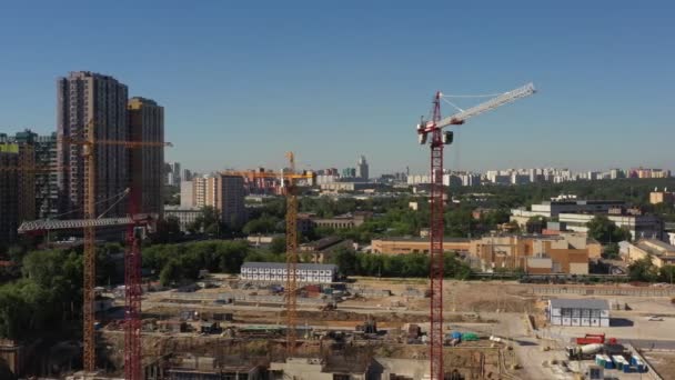 Mehrere Turmdrehkräne beim Bau eines neuen Wohnkomplexes vor dem Hintergrund fertiggestellter gemauerter Mehrfamilienhäuser in einer wohlhabenden Gegend von Moskau. Luftbild — Stockvideo