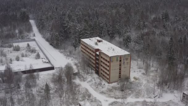 Un edificio abbandonato a più piani dai tempi dell'URSS in una fitta foresta in un paesaggio invernale. casa abbandonata nella foresta invernale. vista aerea — Video Stock