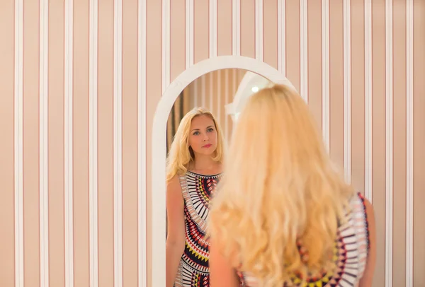 Woman in a dress looks in the mirror — Stock Photo, Image