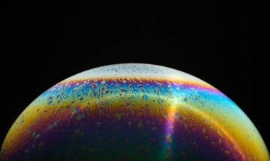 Siyah arka planda gökkuşağı renginde bir baloncuk. Yakın plan. Yan görüş. Parlak renkler. Bilinmeyen bir gezegenin taklidi.