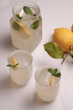 Sürahi ve masada buz gibi iki limonata ve limon. Nane limonatasını beyaz mermer bir masada gözlüklerle tazeliyorum. Üst görünüm.