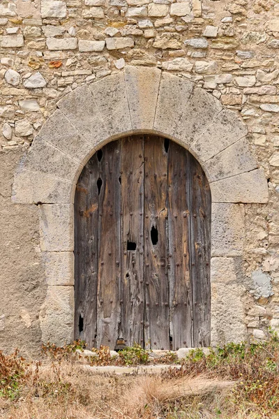 Facade of an old abandoned house with an old and rotten door.