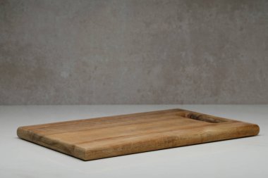 Eski beyaz mermer yüzey ve gri beton üzerinde tahta kesme tahtası. Ürün veya metin için kopyalama alanı olan ön görünüm.