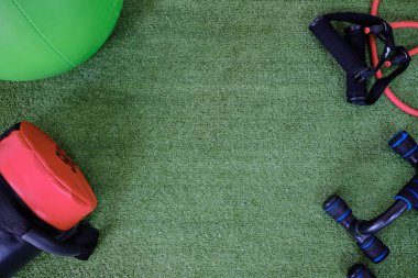 Çim arka planda spor aletleri, düz yatış. Mesaj için yer var. Sağlıklı fikirler.