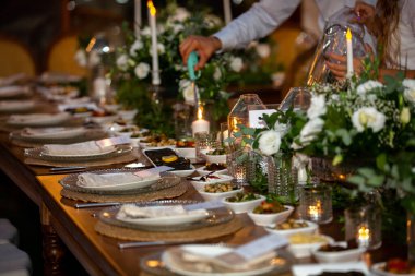 Düğün hazırlama restoranı ve düğün organizatörleri. Sandalyeler ve balayı masaları mumlarla süslenmiş, çatal bıçak takımı ve çanak ve masa örtüsüyle servis edilmiş. Düğün alanı, parti alanı