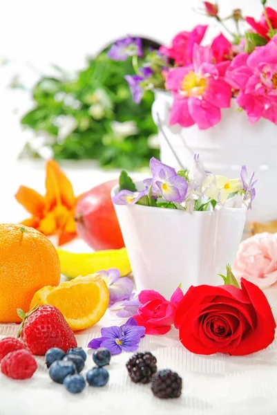 Breakfast brunch table fresh and sunshine morning, flowers, rose, viola, pink strawberry, orange, blueberry, blackberry, pear, pineapple, on yellow tablecloth and wood board, white bowl et rose petal. — Stock Photo, Image