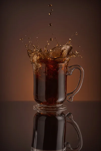 Splash černé kávy izolovaných na hnědé pozadí — Stock fotografie