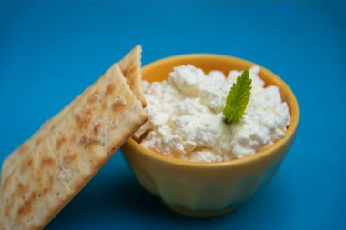 süzme peynir ve krakerler sarı kase ve mavi arka plan, aperatif veya diyet konsepti .