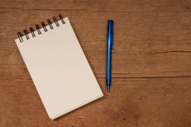 Boş not defteri ve kalem ahşap masanın üzerinde.