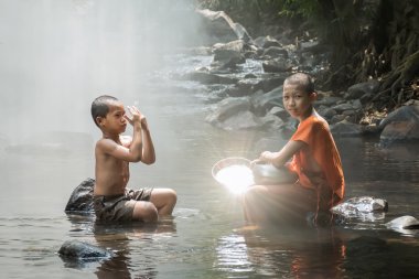 küçük bir keşiş ve güneş ışığından parlama yapıyor küçük bir çocuk.