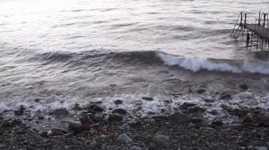 Rusya 'da Novorossiysk yakınlarındaki Karadeniz kıyısında taştan bir sahilde sörf yapmak.