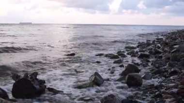 Rusya 'da Novorossiysk yakınlarındaki Karadeniz kıyısında taştan bir sahilde sörf yapmak.