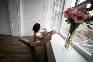 Pencere pervazına ve pencereden dışarı bakıp yakınındaki güzel kız uzanır. Yoga her gün.