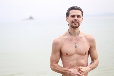 Yakışıklı delikanlı denize karşı. Adam gülümsüyor ve ileri görünüyor.