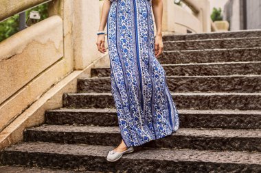 Bacaklar merdivenlerden aşağı gelen bir kızın fotoğrafı. Kız uzun elbise ile.