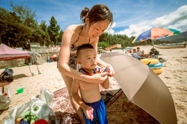 Genç Anne küçük oğlu kumsalda giyinme