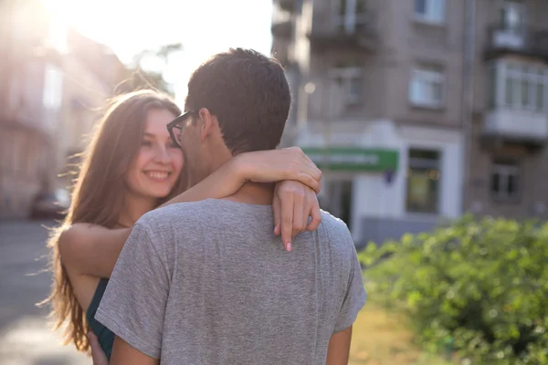 Jovem menina bonita olha para o menino abraçando seu e sorrindo — Fotografia de Stock