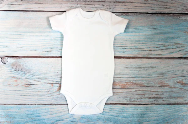 木製の背景に白い赤ん坊のボディスーツのモックアップ 様式化されたストック写真 モックアップ — ストック写真