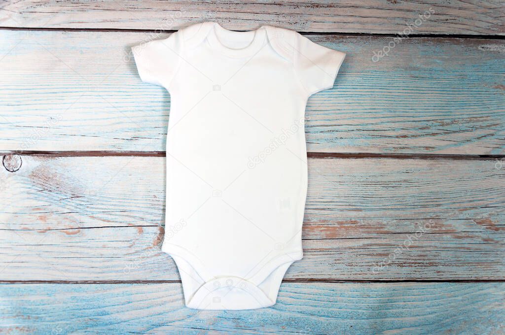White baby bodysuit mockup on wooden background. Styled stock photography. Mock up.