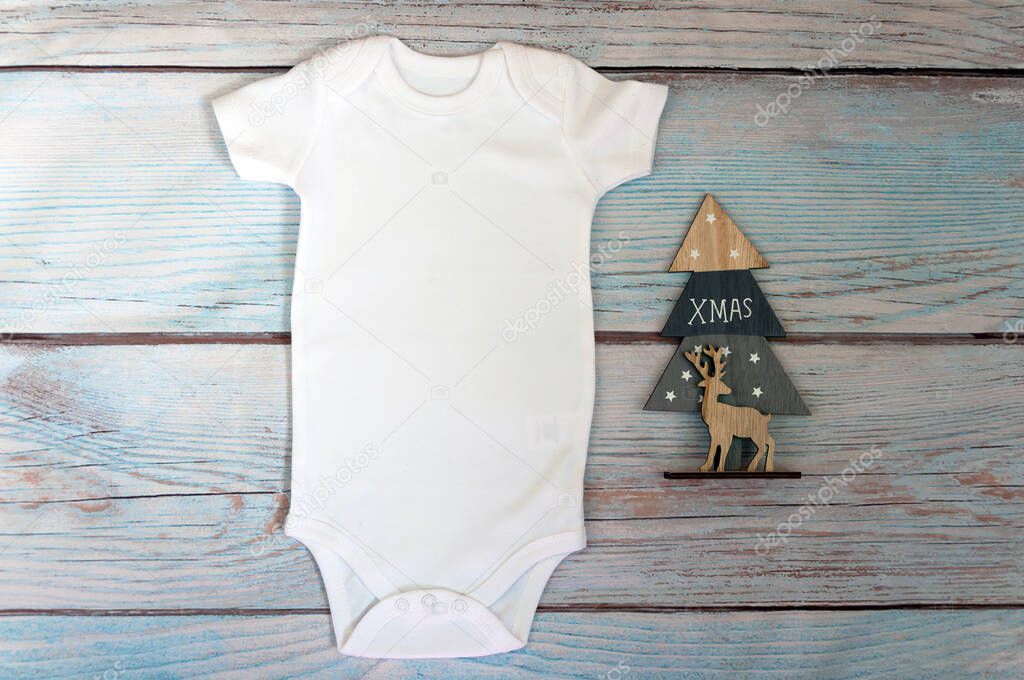 Christmas White baby bodysuit mockup on wooden background. Styled stock photography. Mock up.