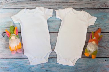 Düzen Düz, tahta bir arka planda cüce oyuncakları olan iki beyaz bir bebek tulumu giy. Logo dizaynı ve yerleştirme planı, reklamcılık. Styled Stock fotoğrafçılık, stok fotoğrafı. düz yat.