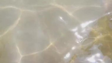 Su dalgalarının üst görünümü ve güneş ışığı yansıması arkaplanı.