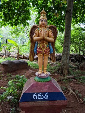 a long shot of standing Garuda statue in Natural arch rock garden in Tirumala: Tirumala, Andhra Pradesh, India-July 10.2021 clipart