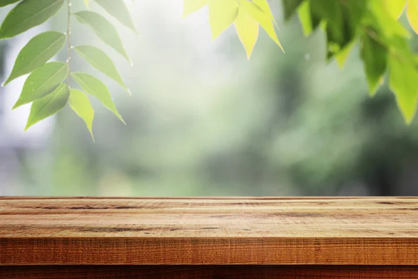 木製テーブルと空のぼやけた緑の葉製品のための自然背景 — ストック写真