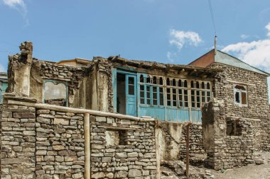 Kafkas köyünde tipik taş evler. Azerbaycan 'ın fakir köyü. Eski bir dağ köyündeki basit kırsal evler. Ahşap kapıları ve taş duvarları olan geleneksel köy çiftlik evi..
