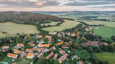Aerial view of idyllic hilly landscape and small village.Houses from above, real estate concept.Natural summer scenic countryside. Beautiful view of green valley,meadows and lake in the Czech republic clipart