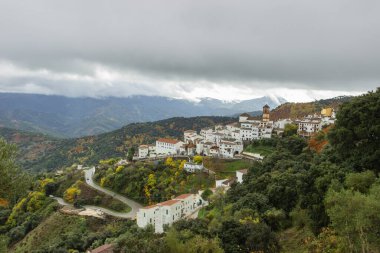 Tipik beyaz Endülüs köyü, dağları gören pueblo blanco. Bulutlu, sisli bir sonbahar günü. Beyaz evler kırmızı çatı. Şehir manzarası. İspanya 'da emlak.