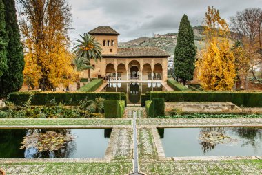Granada, İspanya - 25 Kasım 2018. Alhambra kompleksi yakınlarındaki Generalife bahçeleri. Çiçek yatakları, çeşmeler, sütunlar ve köşkler çerçeveli havuz. Ünlü UNESCO sitesi. Alhambra sarayı ve bahçeleri.