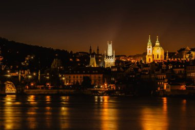 Karluv 'un en çok yansıttığı yer Vltava Nehri. Prag, Çek Cumhuriyeti 'nin akşam panoraması. Uzun metrajlı şehir ışıkları. Avrupa şehir manzarası. Şehir seyahati kavramı.