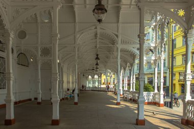 Karlovy Vary, Çek Cumhuriyeti-12 Eylül 2020. Çek ünlü spa şehrindeki Mill Colonnade manzarası. Bohemya 'nın romantik mimarisi. İnsanlar kaplıcadan içme suyu içip oturuyorlar.