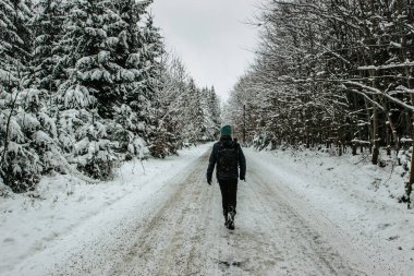 Kar ve buzla kaplı yolda yürüyen aktif bir kız. Soğuk kış panoramaları, asfalt yollar. Hava tahmini. Seyahat özgürlüğü arka plan fotokopisi..