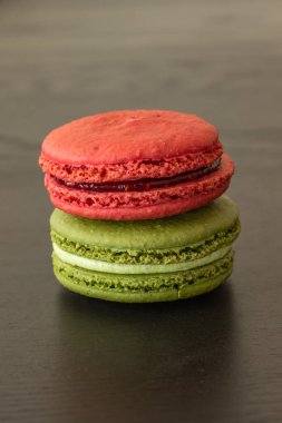 Tatlı ahududular ve şam fıstıklı kurabiyeler koyu ahşap arka planda izole edilmiş. Fransız pastası. Küçük lezzetli Fransız pastaları. Geleneksel Fransız tatlıları. Yakın plan.