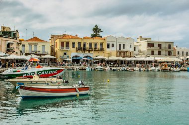 Rethymno, Girit - 9 Ekim 2019. Balıkçı tekneleri, renkli evler, restoranlar, sahil tavernaları ve kafeleri olan Rethymno Venedik Limanı manzarası. Yunanistan 'da Ortaçağ kenti tatili.