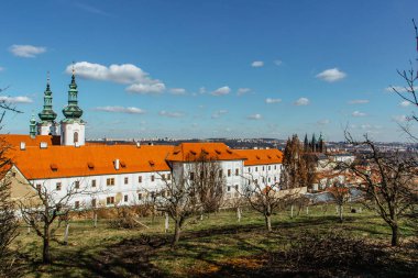 Güneşli bir günde arka planda kilise, bahçeler ve Prag Kalesi olan Strahov Manastırı manzarası. Bohemya 'nın en eski Premonstratensian manastırı. Tarihi turistik cazibe.