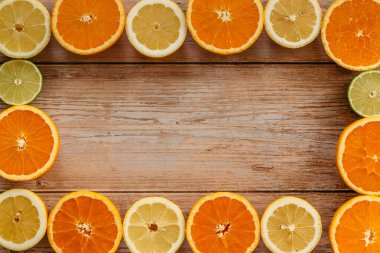 Portakallar, limonlar ve limonlar yukarıdan ahşap masa manzarasına kayar. Taze meyvelerin yarısıyla güzel bir arka plan. Sağlıklı beslenme, vitamin C.Summer tropikal meyve konsepti düzlüğü. Yaratıcı çerçeve