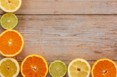 Portakallar, limonlar ve limonlar yukarıdan ahşap masa manzarasına kayar. Taze meyvelerin yarısıyla güzel bir arka plan. Sağlıklı beslenme, vitamin C.Summer tropikal meyve konsepti düzlüğü. Yaratıcı çerçeve
